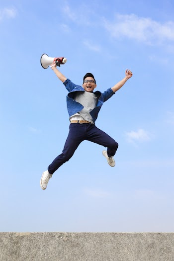 man jump and shout by megaphone with blue sky background, asian