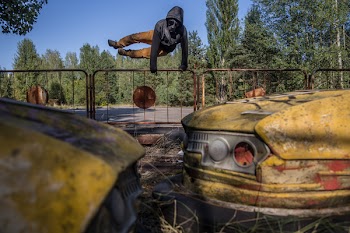 Man Jumping on Brown Metal Fence Towards Two Yellow Bump Cars