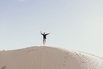 man jumping on brown sand during daytime