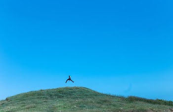 man jumping on cliff at daytime