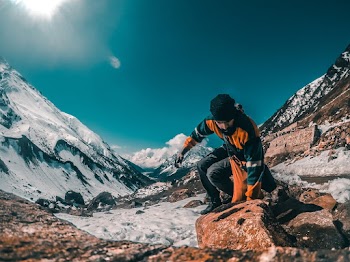 Man jumping over a brown rock  on a mountain