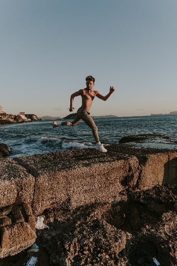 Man Jumping over Brown Barricade Near Shore