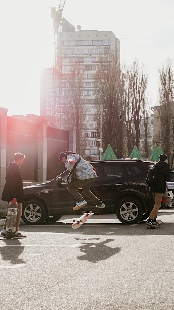 Man Jumping over Skateboard Beside Vehicle