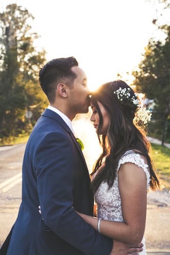 man kissing forehead of woman while hands on hips
