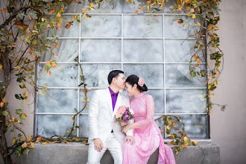 Man Kissing Woman's Forehead While Sitting on Concrete Surface Near Glass Window