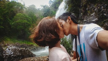 Man Kissing Woman Behind Waterfalls