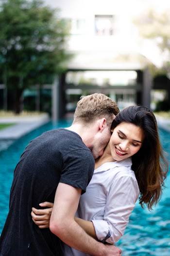 Man Kissing Woman on Neck Near Swimming Pool