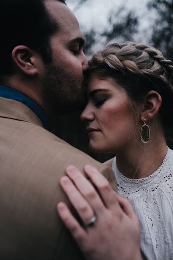 man kissing woman's forehead