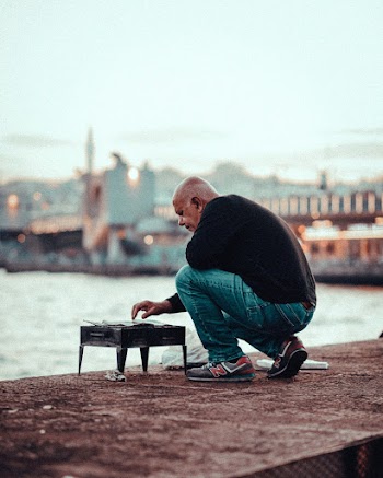 Man Kneeling Near Body of Water