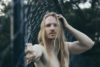 Man Leaning Against Chain Link Fence