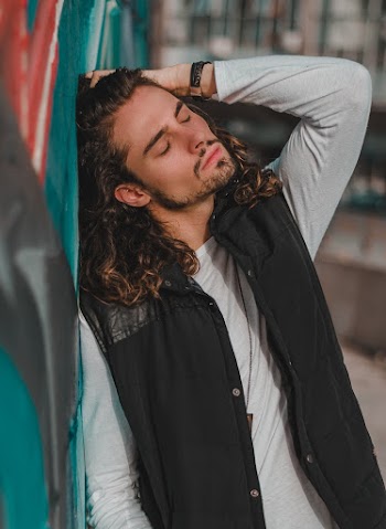 Man Leaning on Blue Graffiti Wall