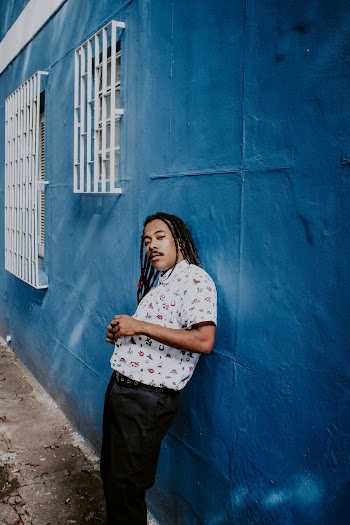 Man Leaning on Blue Wall Near Window
