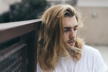 Man Leaning on Brown Fence Outside