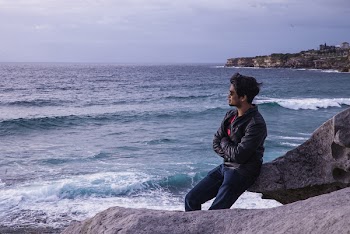 Man Leaning on Rock Near Beach Shore