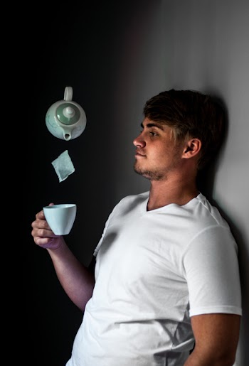 Man Leaning on Wall While Holding White Ceramic Cup 