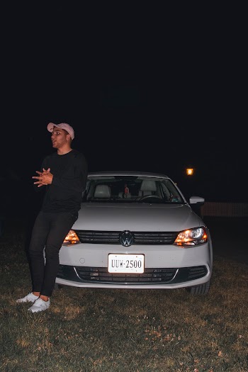 Man Leaning On White Volkswagen Vehicle At Night