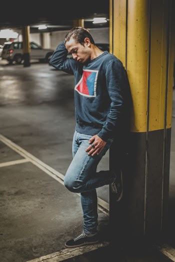 Man Leaning on Yellow and Gray Metal Post