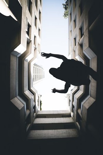 man leaps in middle of high-rise buildings