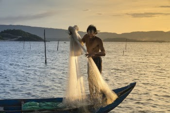 Man Lifting Fish Net On Boat