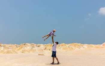 Man Lifting Girl Up While Standing on Sand