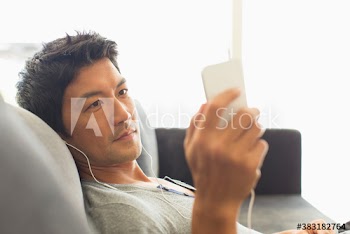 Man listening to music with headphones and smart phone on sofa