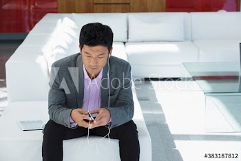 Man listening to music with mp3 player and headphones on sofa