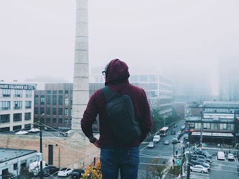 man looking down the city covered with fogs during daytime