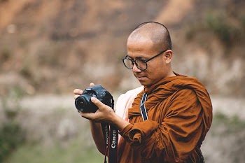 man looking on black DSLR camera on hands