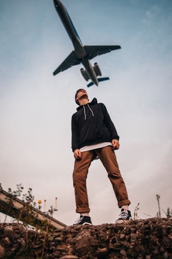 man looking up at flying airplane during daytime