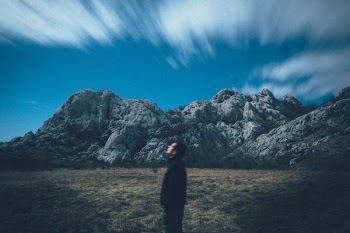 man looking up the sky located across the rock formation