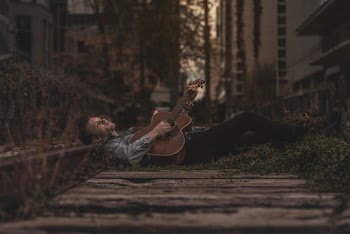 Man Lying Down on Ground While Playing Guitar