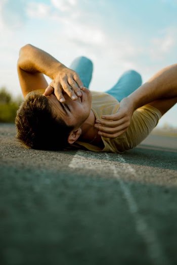 man lying on road during daytime