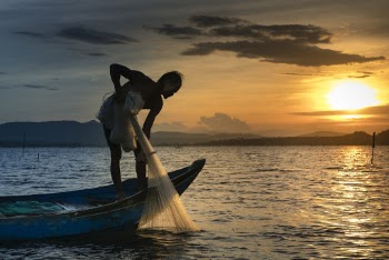Man on Boat Holding White Mesh Fishing Net