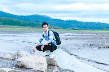 Man on Gray Rock Beside Body of Water
