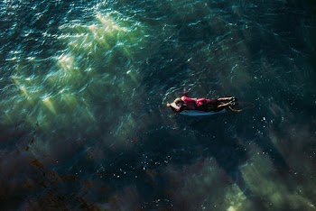 Man on Surfboard Swimming in Water