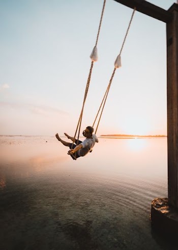 man on swing near body of water