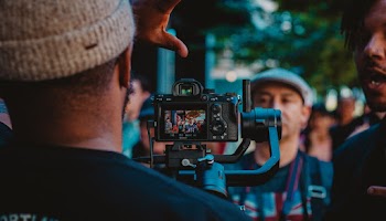 Man Operating Camera In Front Of People