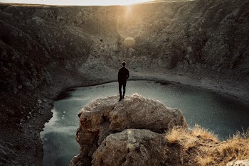 Man Overlooking a Lake from a Cliff