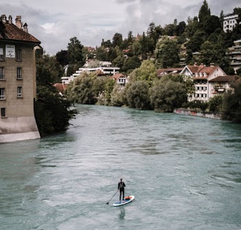 Man Paddling on Paddle Board Between Houses