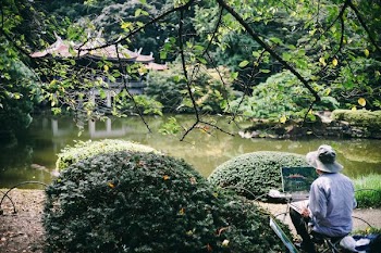 man painting front of river with temple at daytime