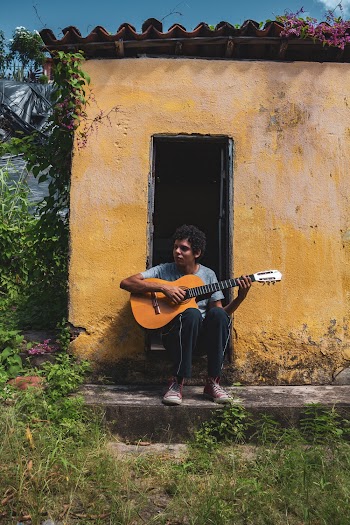 Man Palying Guitar While Sitting on Open Door