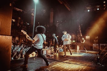 man performing on stage together with his bandmates