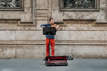man playing brown violin near building at daytime