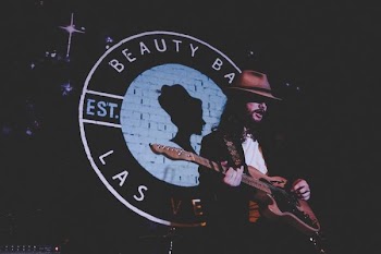 man playing guitar near Las Vegas signage