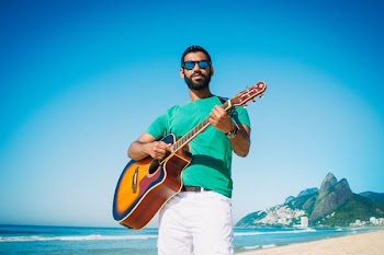 man playing guitar near ocean during daytime