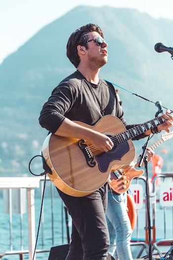 Man Playing Guitar on Stage Near Mountain