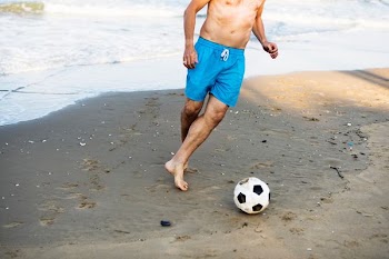 man playing soccer on gray road