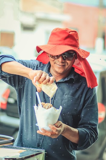 Man Pouring Sauce on Bowl of Street Food