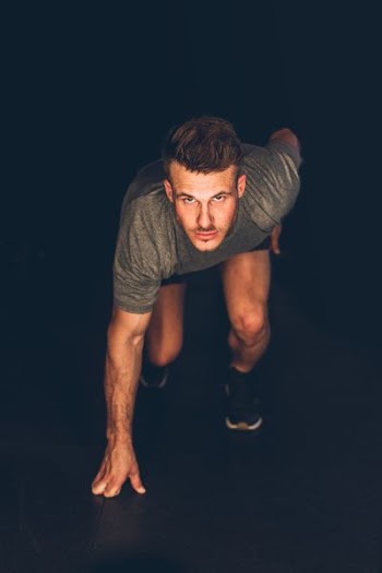 man preparing to run on a dark place