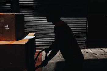 man pushing hand truck with brown boxes